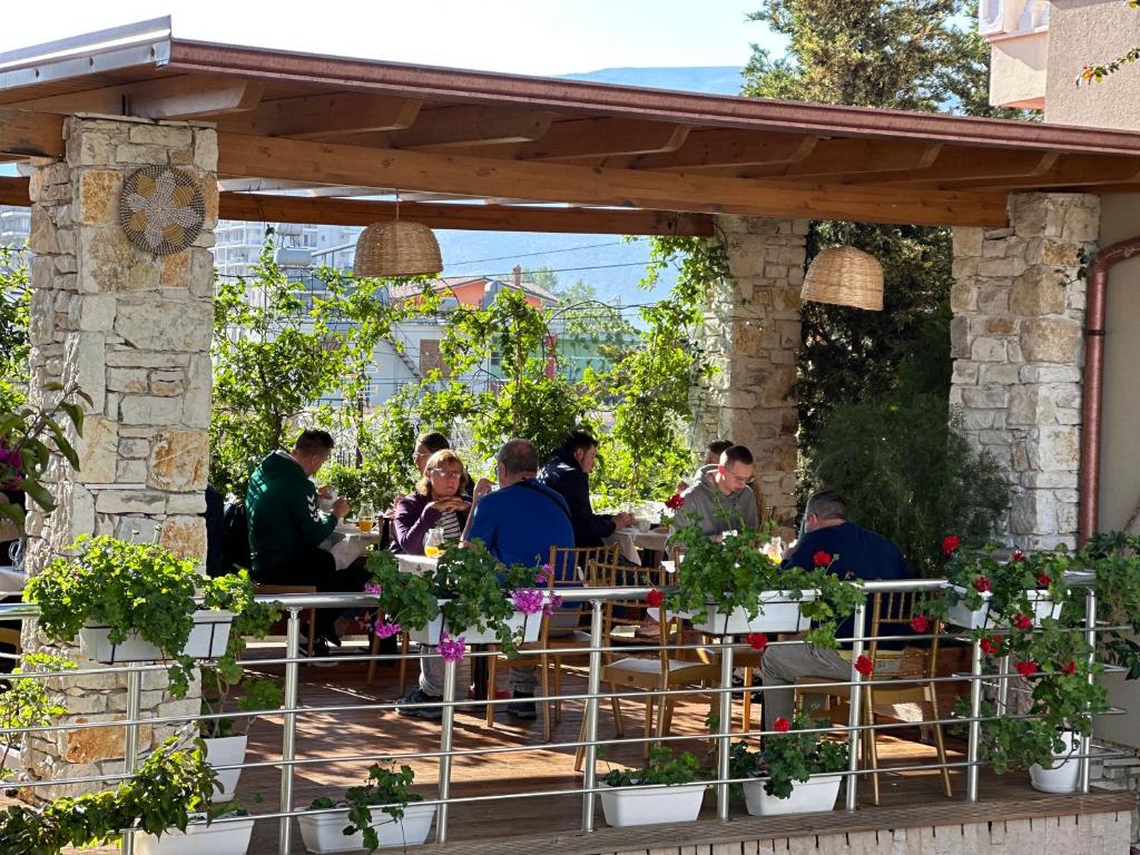a group of people sitting at a restaurant under a pergola at Vila Arial in Vlorë