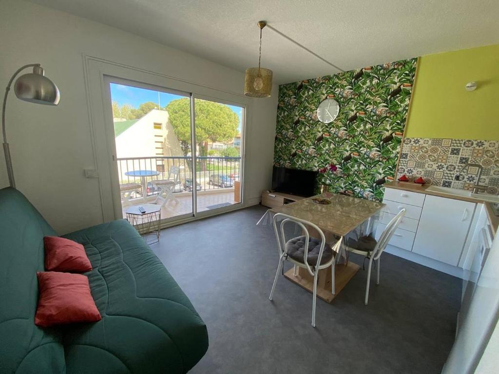 uma sala de estar com um sofá verde e uma mesa em AS24540- P2 neuf à 100m de la Plage em Le Grau-du-Roi