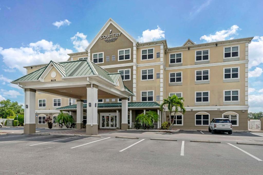 Country Inn & Suites by Radisson, Tampa Airport North, FL في تامبا: مبنى كبير مع سيارة متوقفة في موقف للسيارات