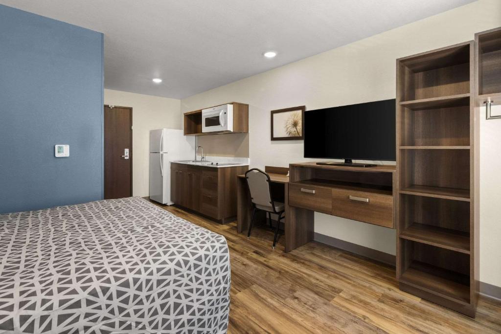 a hotel room with a bed and a desk and a kitchen at WoodSpring Suites Bowling Green I-65 in Bowling Green