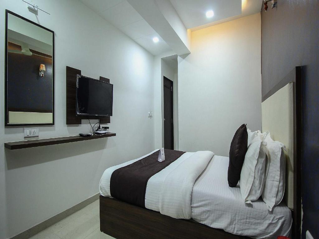 a bedroom with a bed and a flat screen tv at OYO Hotel Dream Inn in Sarkhej