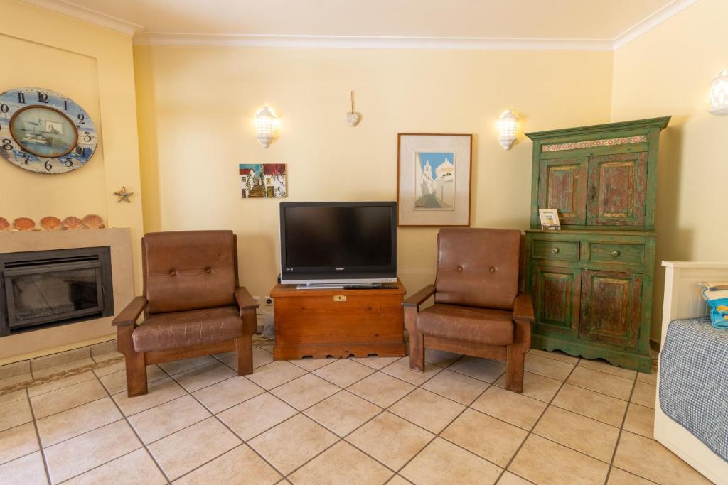 uma sala de estar com duas cadeiras e uma televisão em Urban Beach - Casa MM em Carvoeiro