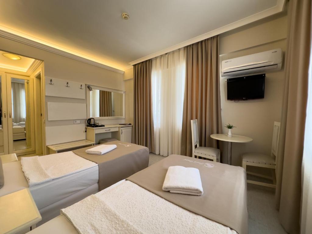 a hotel room with two beds and a television at Savk Hotel in Alanya