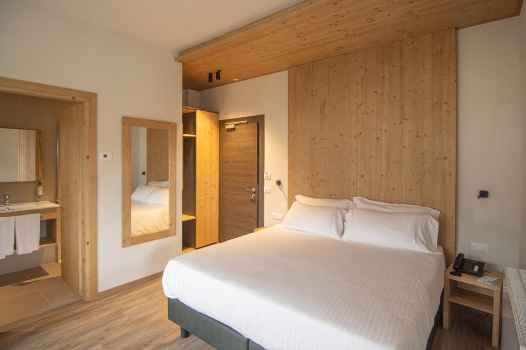 a bedroom with a large white bed and a bathroom at Chalet Cridola Dolomiti Experience in Lorenzago