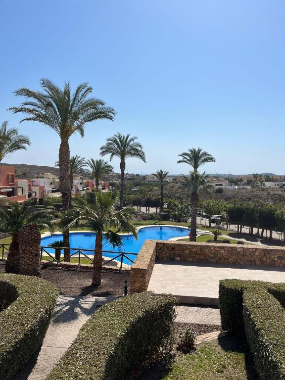 vistas a una piscina con palmeras y arbustos en Apartamento de Lujo Alm. Golf Resort, Valle del Este en Vera