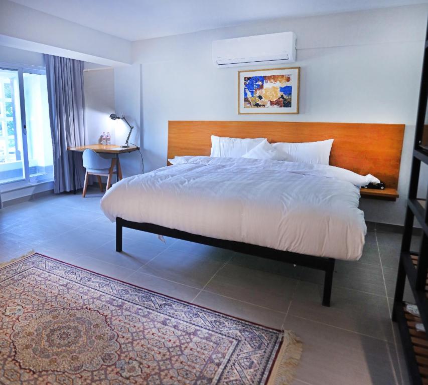 1 dormitorio con 1 cama grande y cabecero de madera en The Avenue Hotel en Islamabad