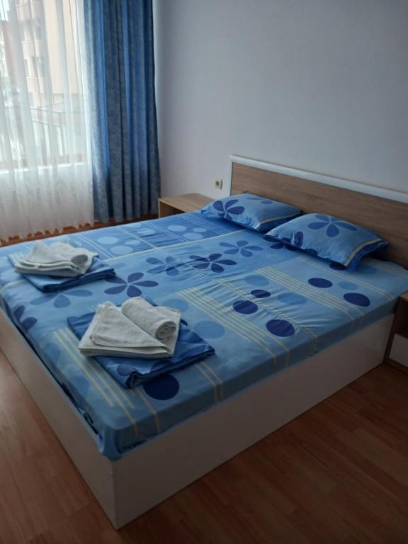 Guest House Vasilevi في نيسيبار: سرير مع لحاف أزرق ومناشف عليه