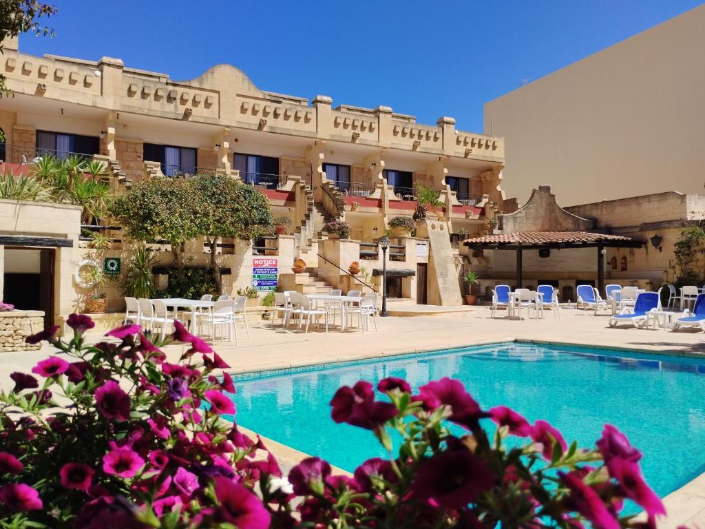 a hotel with a swimming pool in front of a building at Cornucopia Hotel in Xagħra