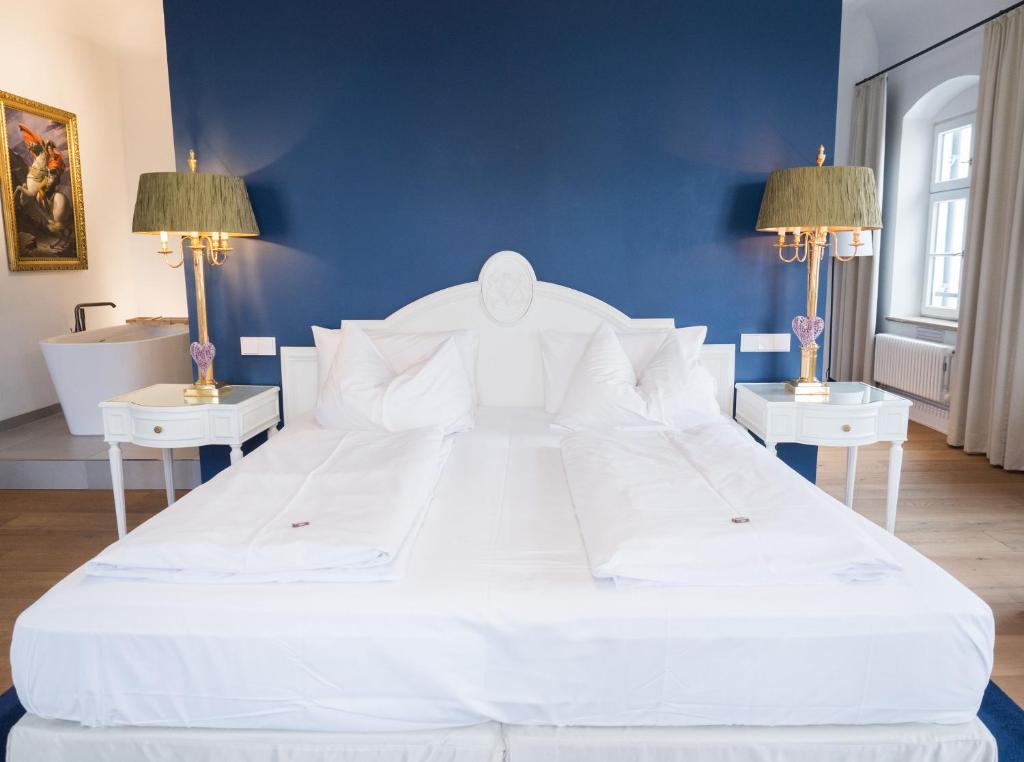 uma grande cama branca num quarto azul com duas mesas em Hotel & Restaurant Posthalterei em Zusmarshausen