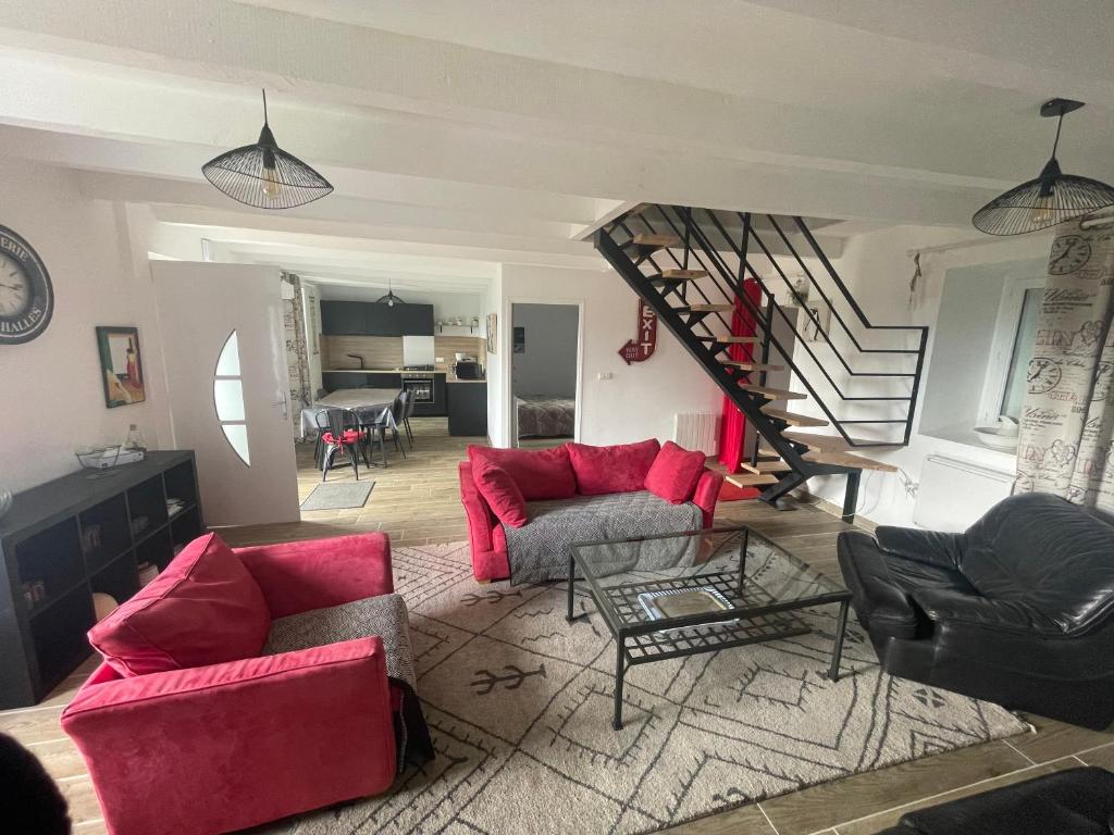 a living room with red furniture and a staircase at Gîte de Montorien 6/7 personnes in Plouguenast Langast