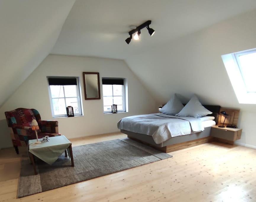 a bedroom with a bed and a chair and windows at Haus im Erholungsgebiet Detern in Detern