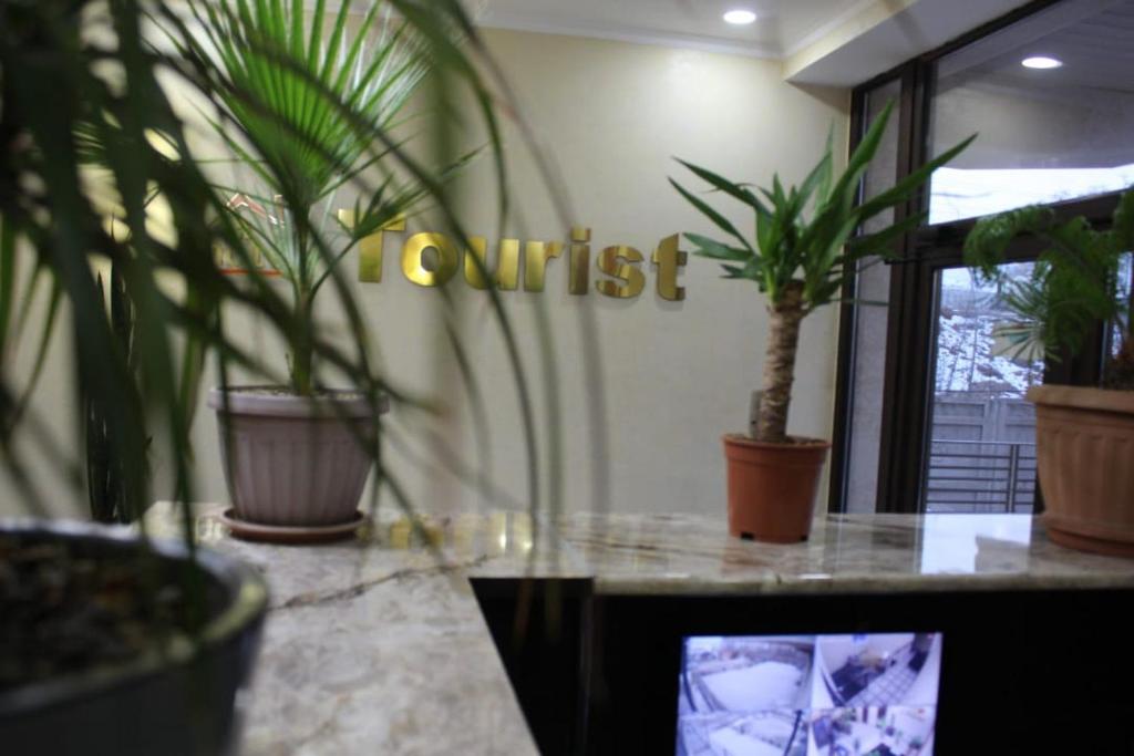 a room with potted plants and a sign that reads contact at hotel Tourist in Karakol