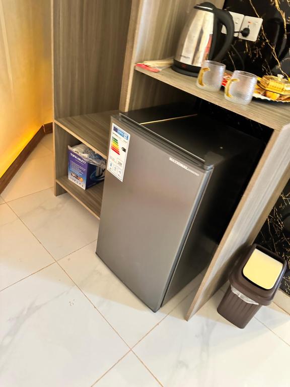 a small refrigerator in a kitchen with a shelf at Wadi Rum Relaxation Camp in Wadi Rum