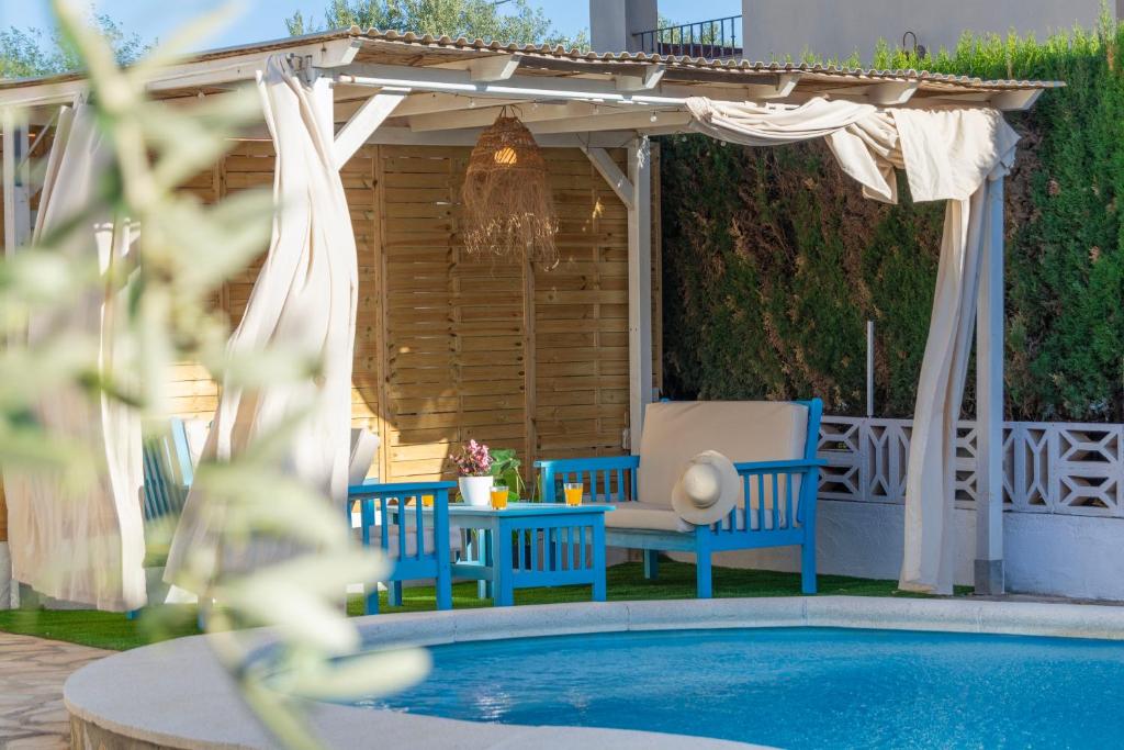 einen Pool mit zwei blauen Stühlen und einer Pergola in der Unterkunft Casa Delicias con Piscina Privada a 200m playa - By Marina Alta Holidays in Denia