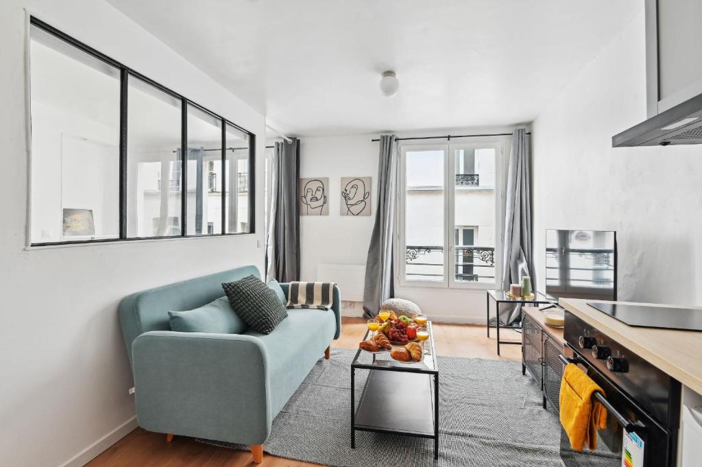 ein Wohnzimmer mit einem blauen Sofa und einigen Fenstern in der Unterkunft Le Marais - CityApartmentStay in Paris