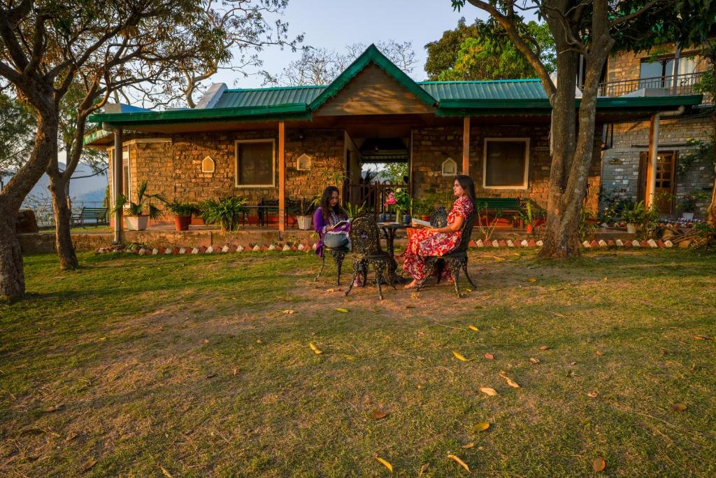 two women sitting at a table in front of a house at Seclude Nahan, Bantony Cottage in Nāhan