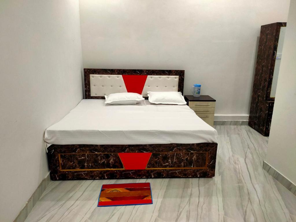 een slaapkamer met een groot bed met witte lakens en rode kussens bij Manglam house in Ayodhya
