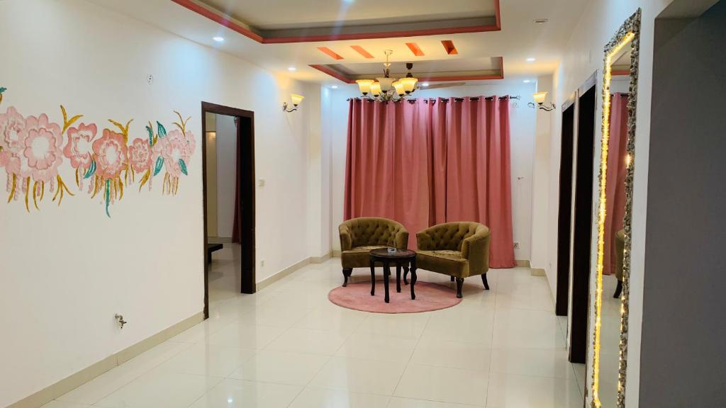 イスラマバードにあるSerene Home Apartment (1-Bedroom)のテーブルと椅子2脚、赤いカーテンが備わるお部屋