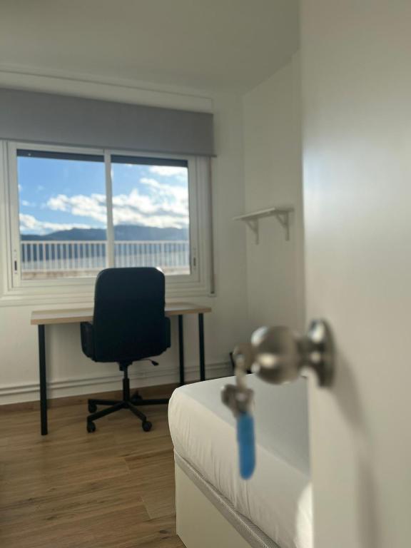 Zimmer mit einem Schreibtisch, einem Stuhl und einem Fenster in der Unterkunft Hab en piso céntrico a 10min del lago in Banyoles