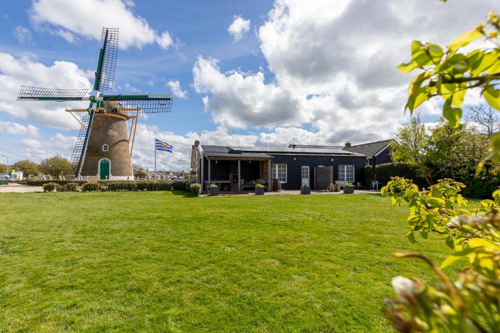 um edifício com um moinho de vento num campo em Molenweg 27a em Zoutelande