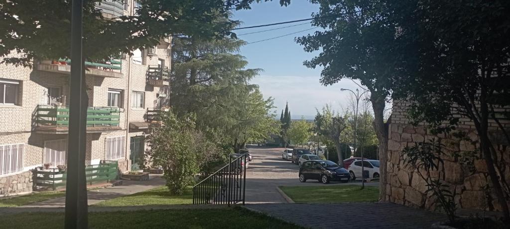 a street with cars parked on the side of a building at Granja de San Antonio in Fresnedillas