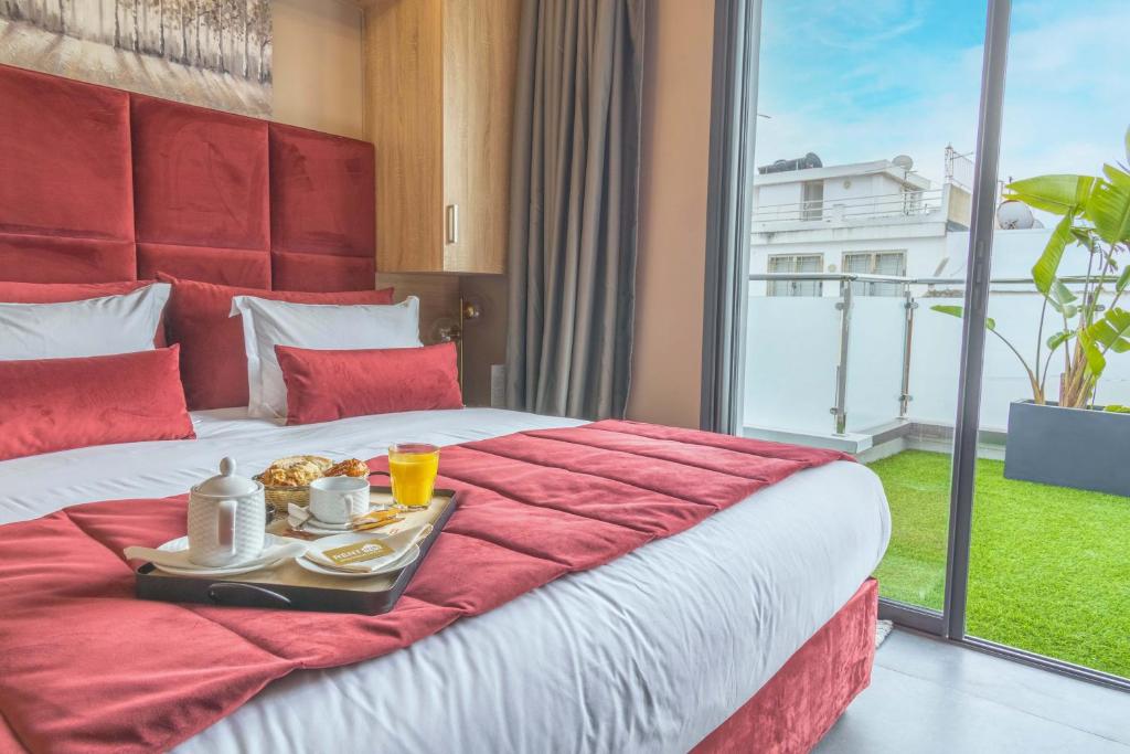 a hotel room with a bed with a tray of food on it at Rent-inn Boutique Hotel in Rabat