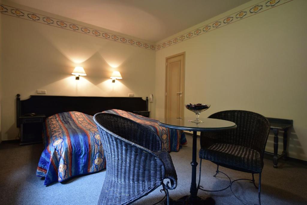 ラ・ロシュ・アン・アルデンヌにあるHôtel Moulin de la Strumentのベッド、テーブル、椅子が備わる客室です。