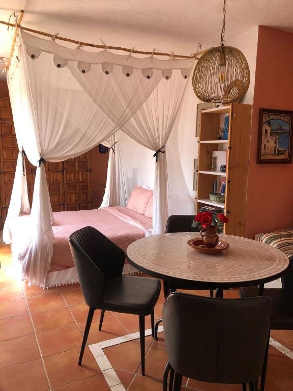 een slaapkamer met een bed, een tafel en stoelen bij Cortijo el Abejaruco in Almuñécar