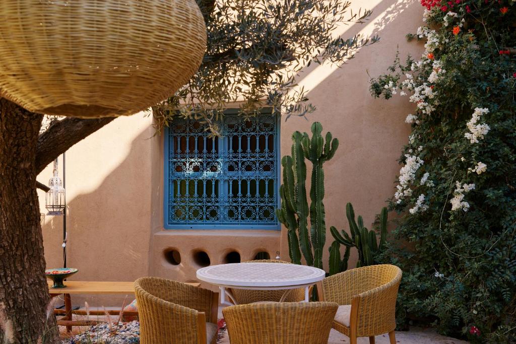 un patio con mesa, sillas y cactus en Agafay Desert Hotel, en El Karia