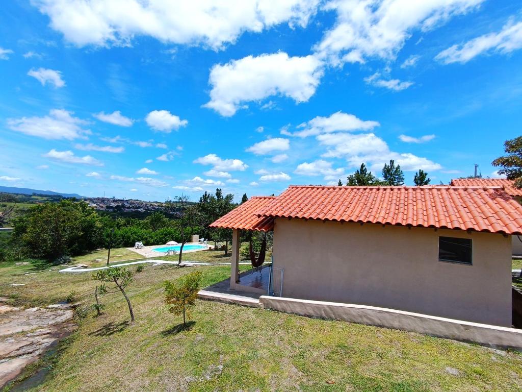 a house with a red roof and a swimming pool at Toca dos Coelhos Chalés in Carrancas