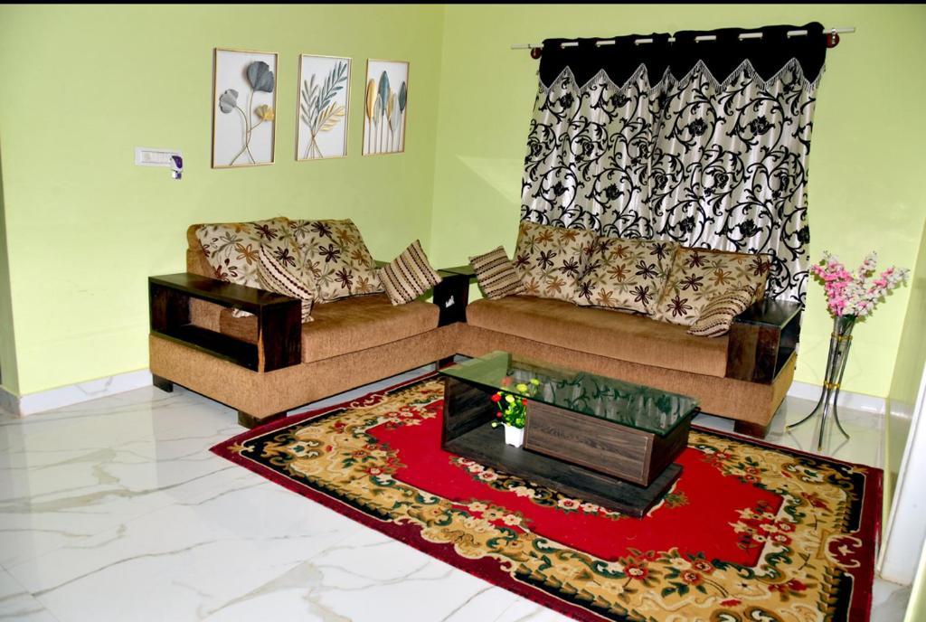 a living room with two couches and a red rug at Royal Guest House in Chikmagalūr