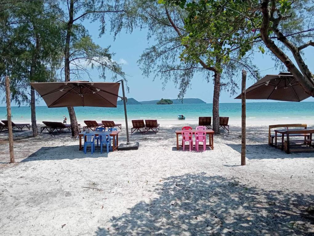 eine Gruppe von Tischen und Stühlen am Strand in der Unterkunft JIJI KOH RONG in Phumĭ Kâoh Rŏng