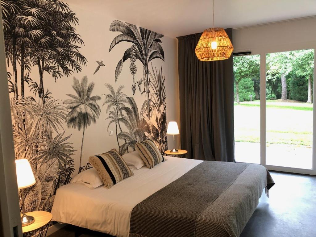 een slaapkamer met een bed met een palmmuurschildering aan de muur bij Le Manoir d'Alexandre in Silfiac