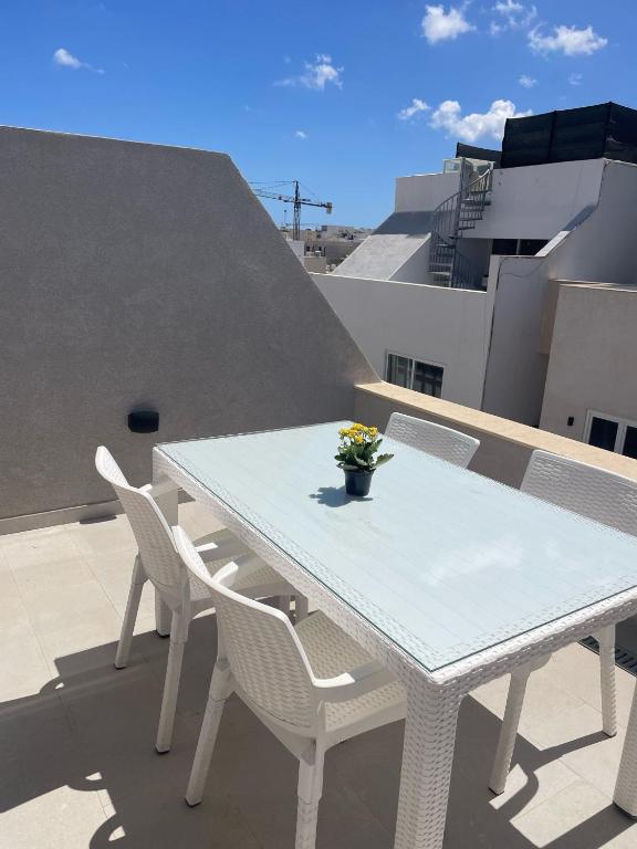 - Balcón con mesa blanca y sillas en Three bedroom penthouse (Privilege Suite), en San Ġwann