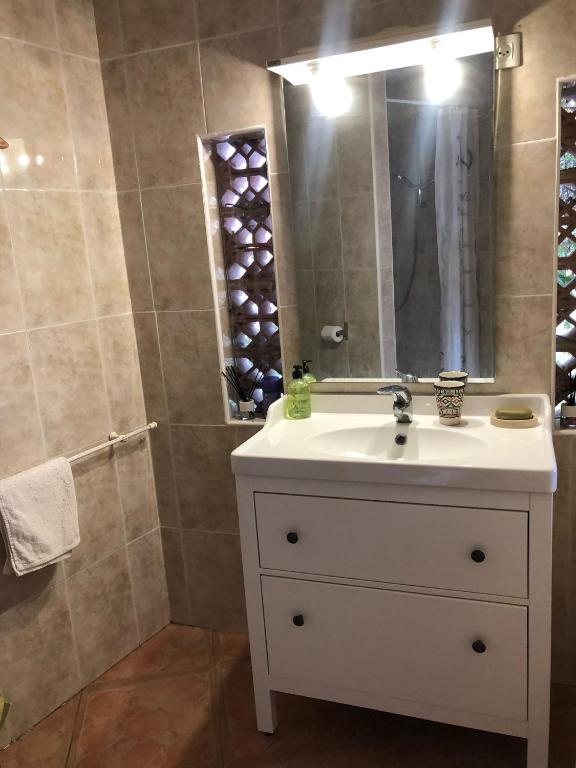een badkamer met een witte wastafel en een spiegel bij Cortijo el Abejaruco in Almuñécar