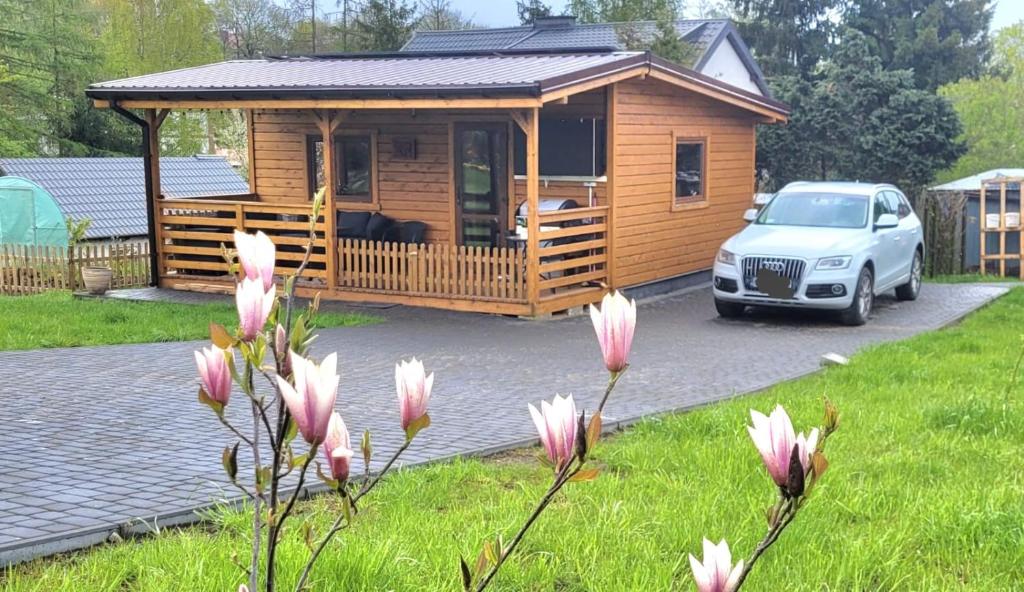 a wooden cabin with a car parked in a yard at Tymek - domek in Miłakowo
