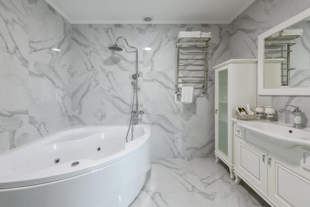 een witte badkamer met een bad en een wastafel bij Sagora Hotel in Tsjernivsi