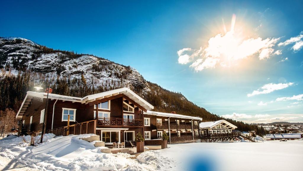 a lodge in the snow in front of a mountain at Eriksgårdens Fjällhotell in Funäsdalen