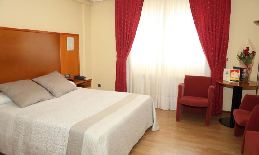 a bedroom with a bed and a chair and a window at Motel Punta Cana in Santiago de Compostela