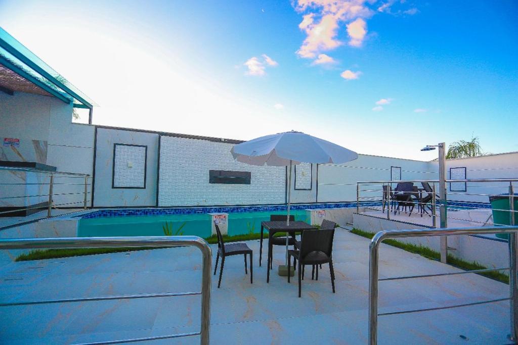 um pátio com uma mesa e um guarda-sol ao lado de uma piscina em Encantos de Taperapuan Duplex em Porto Seguro