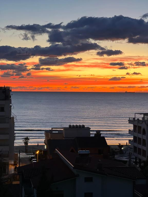 un coucher de soleil sur l'océan avec des bâtiments dans l'établissement Sunset Sea View - Premium Apartment 2BR, à Durrës