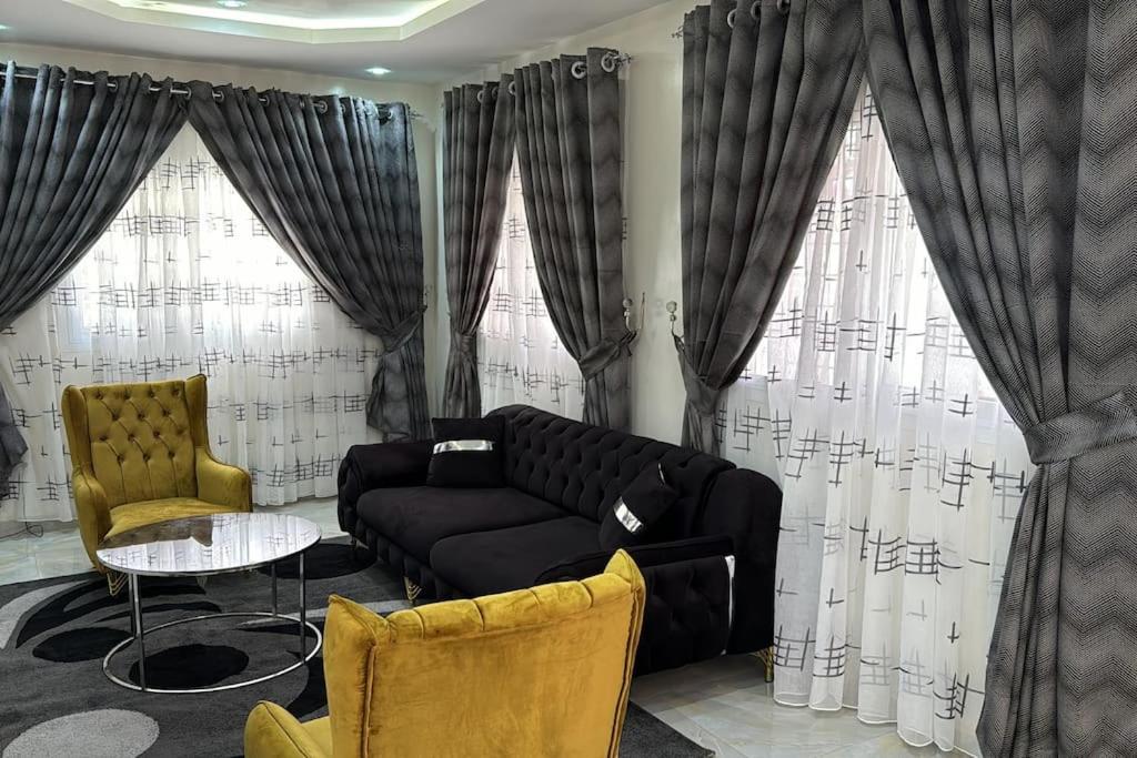 uma sala de estar com um sofá e duas janelas em Sall Residence Mbour, Appartement 3 em Mbour