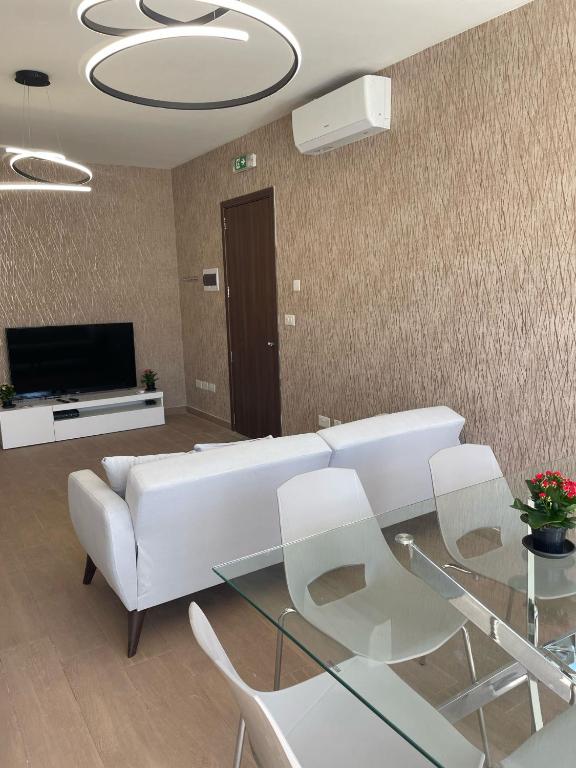 ein Wohnzimmer mit einem weißen Sofa und einem Glastisch in der Unterkunft THREE BEDROOM APARTMENT SAN GWAN in San Ġwann
