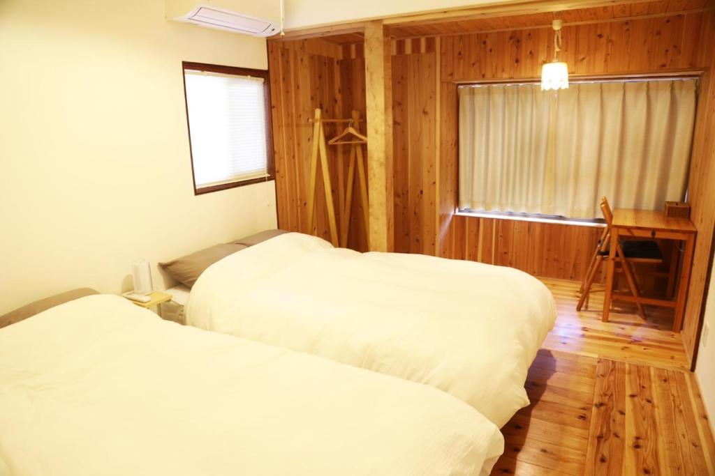 鹿児島市にある小宿　福右衛門邸のウッドウォールと窓が備わるドミトリールームのベッド2台分です。