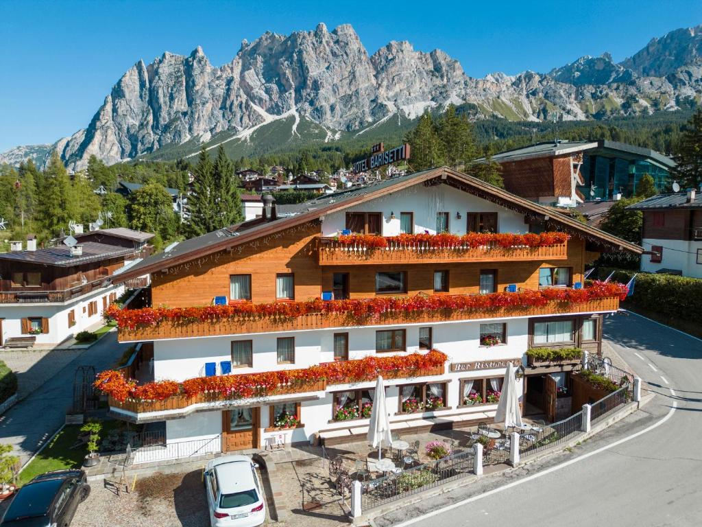 a building with flowers on the roof in front of mountains at Barisetti Sport Hotel in Cortina dʼAmpezzo