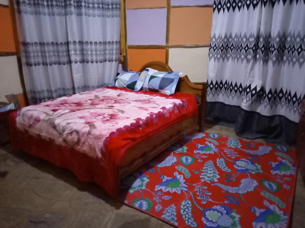 a bed in a room with curtains and a rug at Irente Kinyonga Cottage in Lushoto
