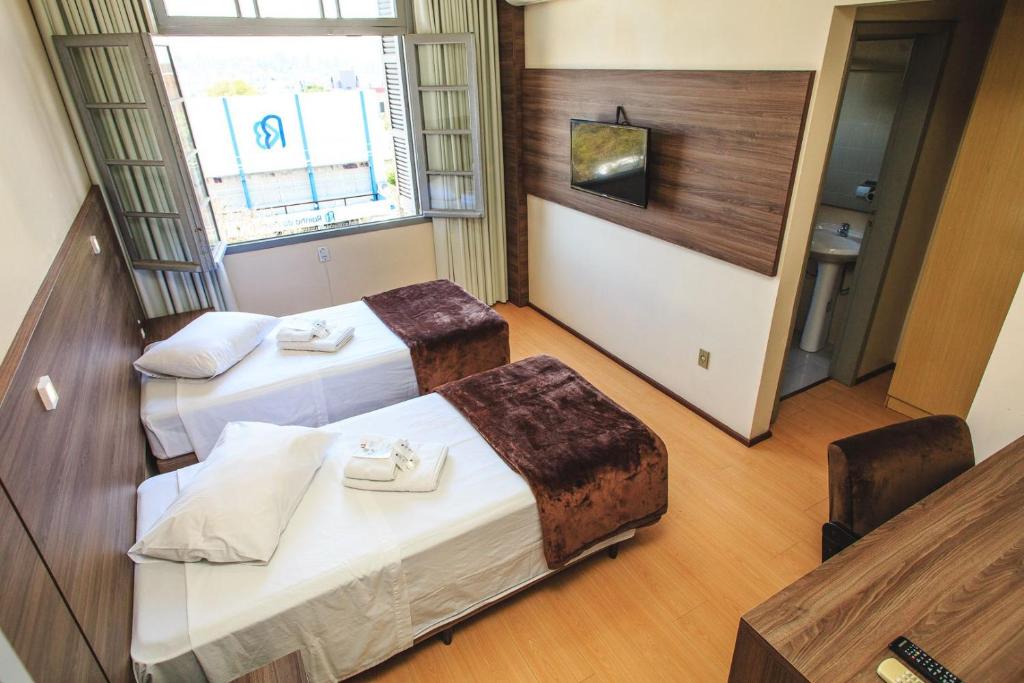 um quarto de hotel com duas camas e uma televisão em Pousada Convento São Lourenço em Porto Alegre