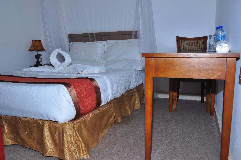 a bedroom with a bed with a desk and a bed sidx sidx sidx at Lamerinn Hotel Juba in Juba