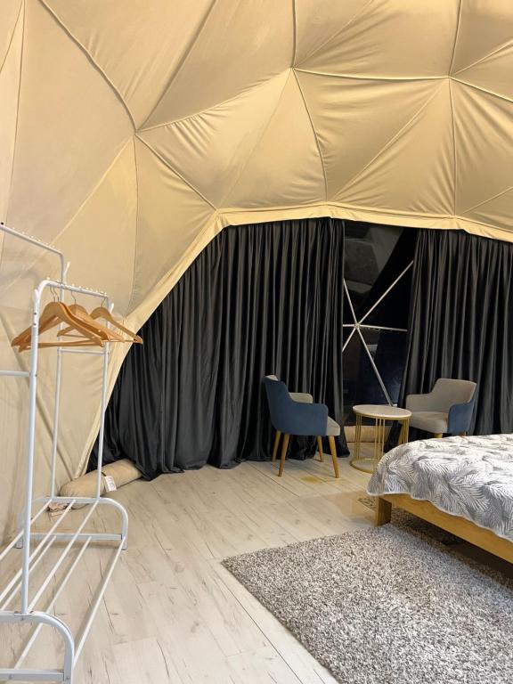 a bedroom with a tent with chairs and a bed at GLAXY_GLAMPING in Karakol