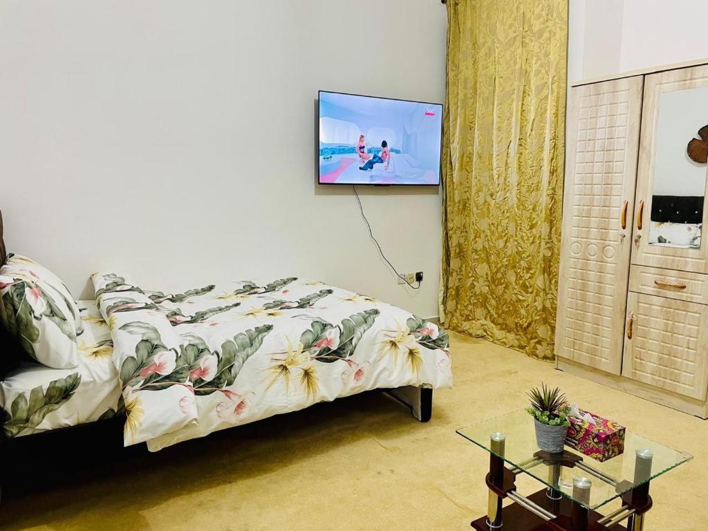 a bedroom with a bed with a tv on the wall at Relaxation Quiet Room Apartment in Abu Dhabi